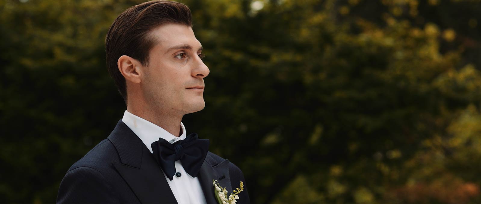 Groom reacts to his bride walking down the aisle during outdoor wedding ceremony