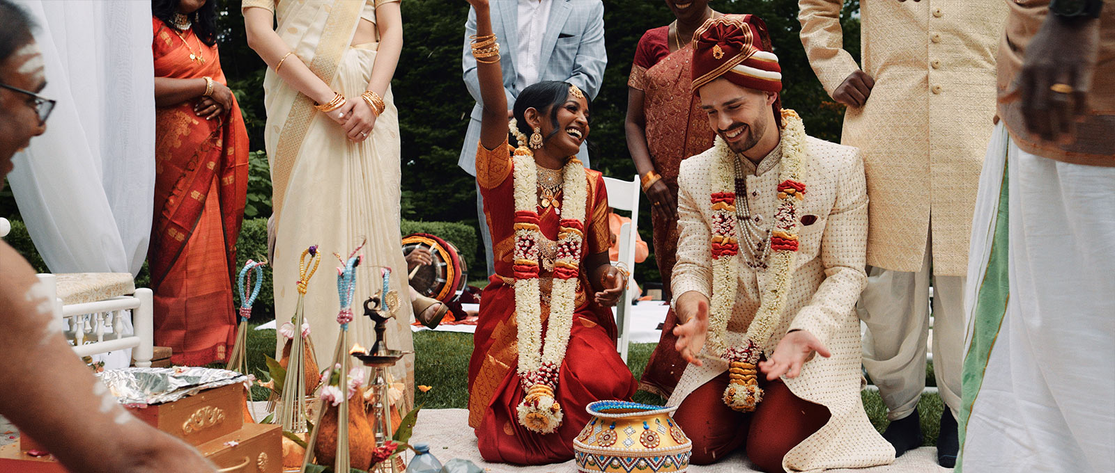 Candid moment of laughter between a bride and groom during their traditional outdoor Hindu ceremony.