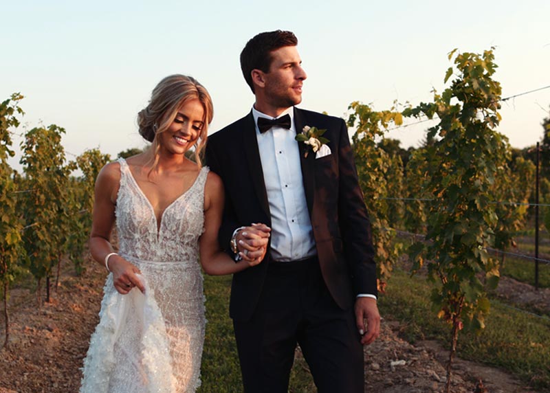 Aryne and John Tavares walk down a vineyard at their Niagara on the Lake wedding