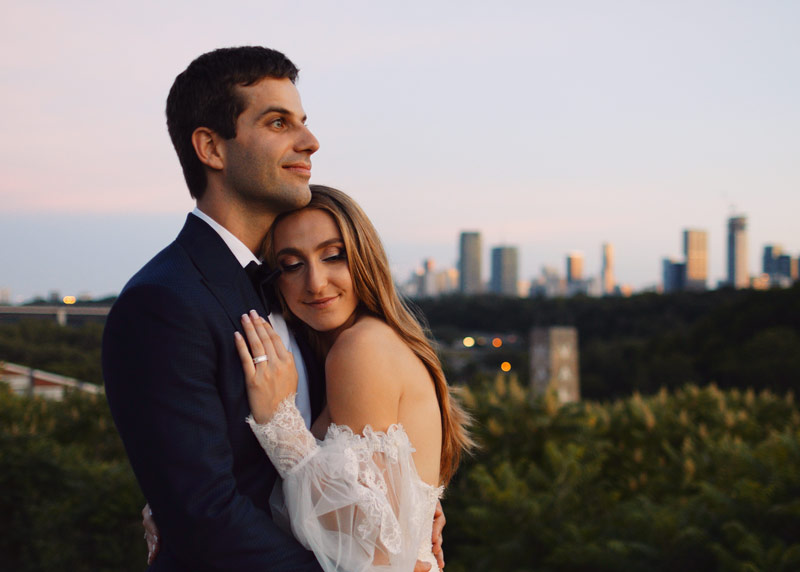 Couple overlooks the Toronto skyline from their Evergreen Brickworks wedding at sunset.